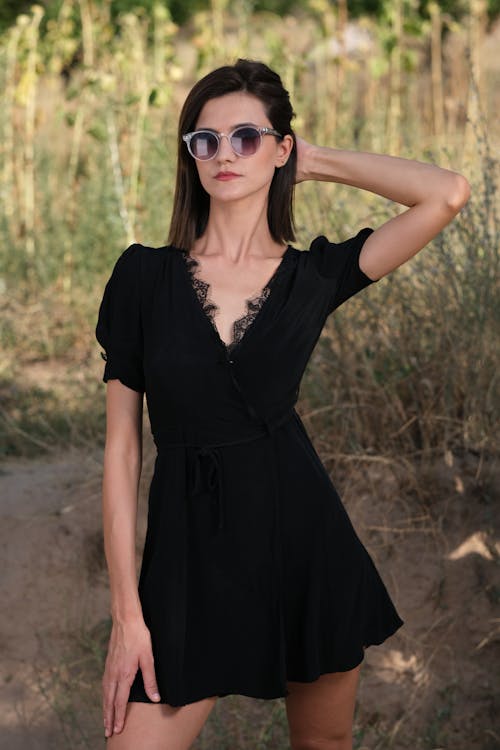 Portrait of a Female Model Wearing Sunglasses and a Black Dress Posing Outdoors