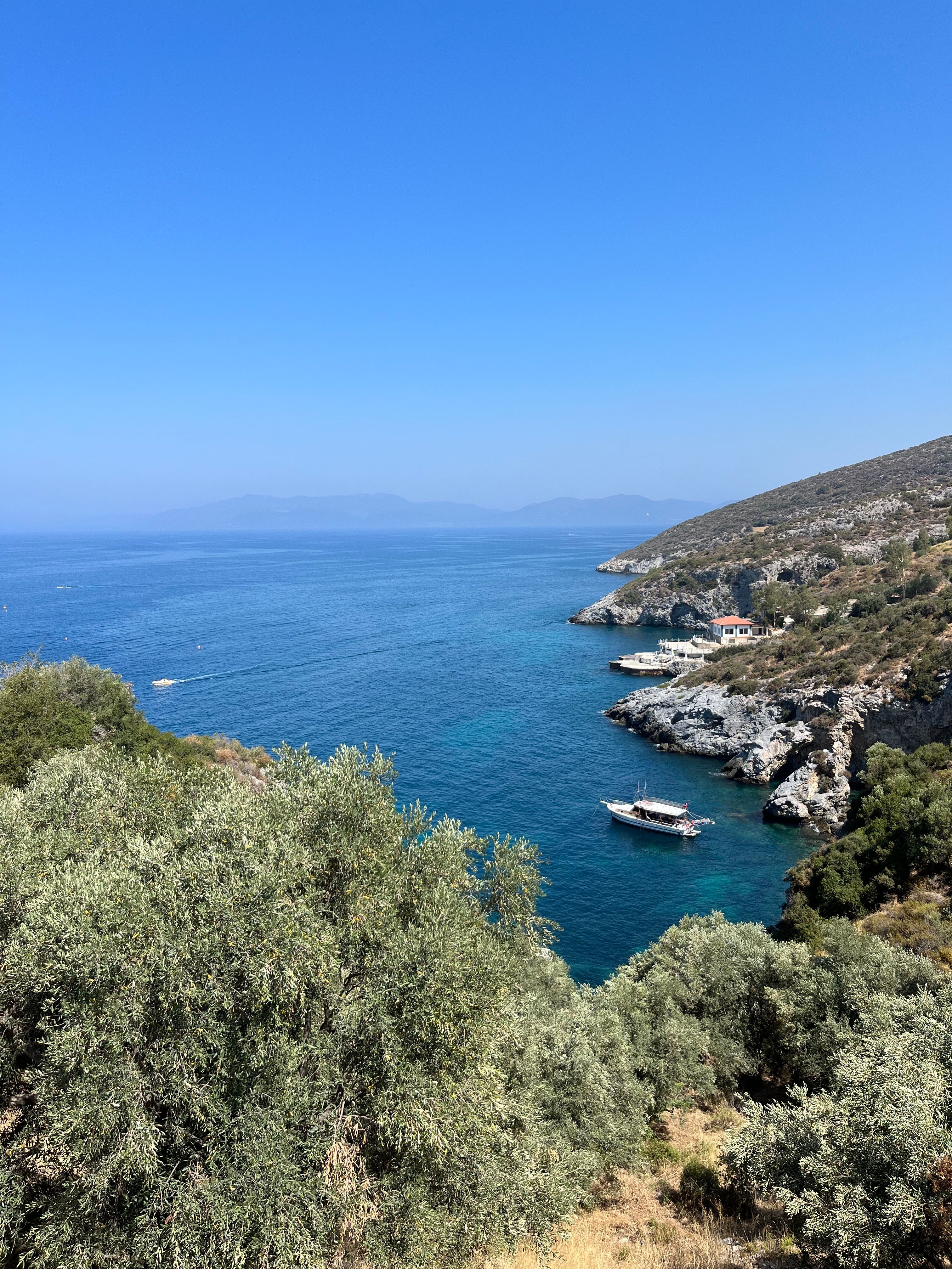Stunning view of the Aegean coastline in Kuşadası, Türkiye, featuring clear blue waters and rocky landscapes.