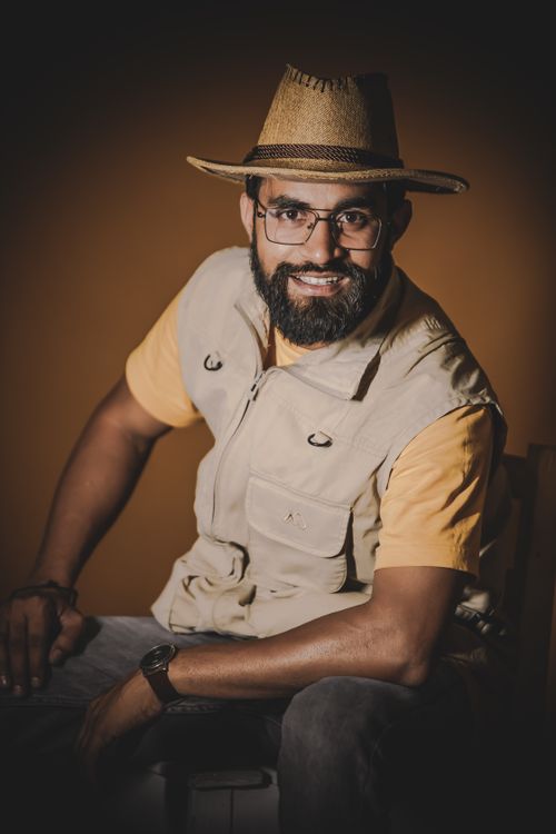 Free Portrait of a man with a beard and eyeglasses wearing a hat, smiling confidently. Stock Photo