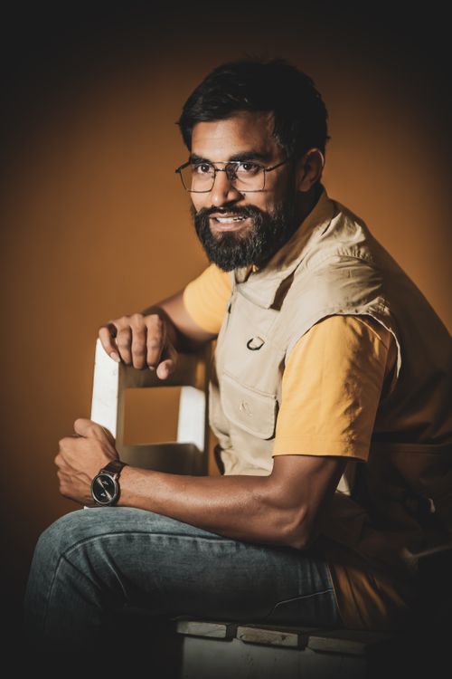 Free Portrait of a mid adult man with a beard wearing eyeglasses and waistcoat, seated against a warm background. Stock Photo