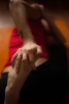 Intimate close-up of a person in yoga pose, hand holding foot with focus on movement and form.