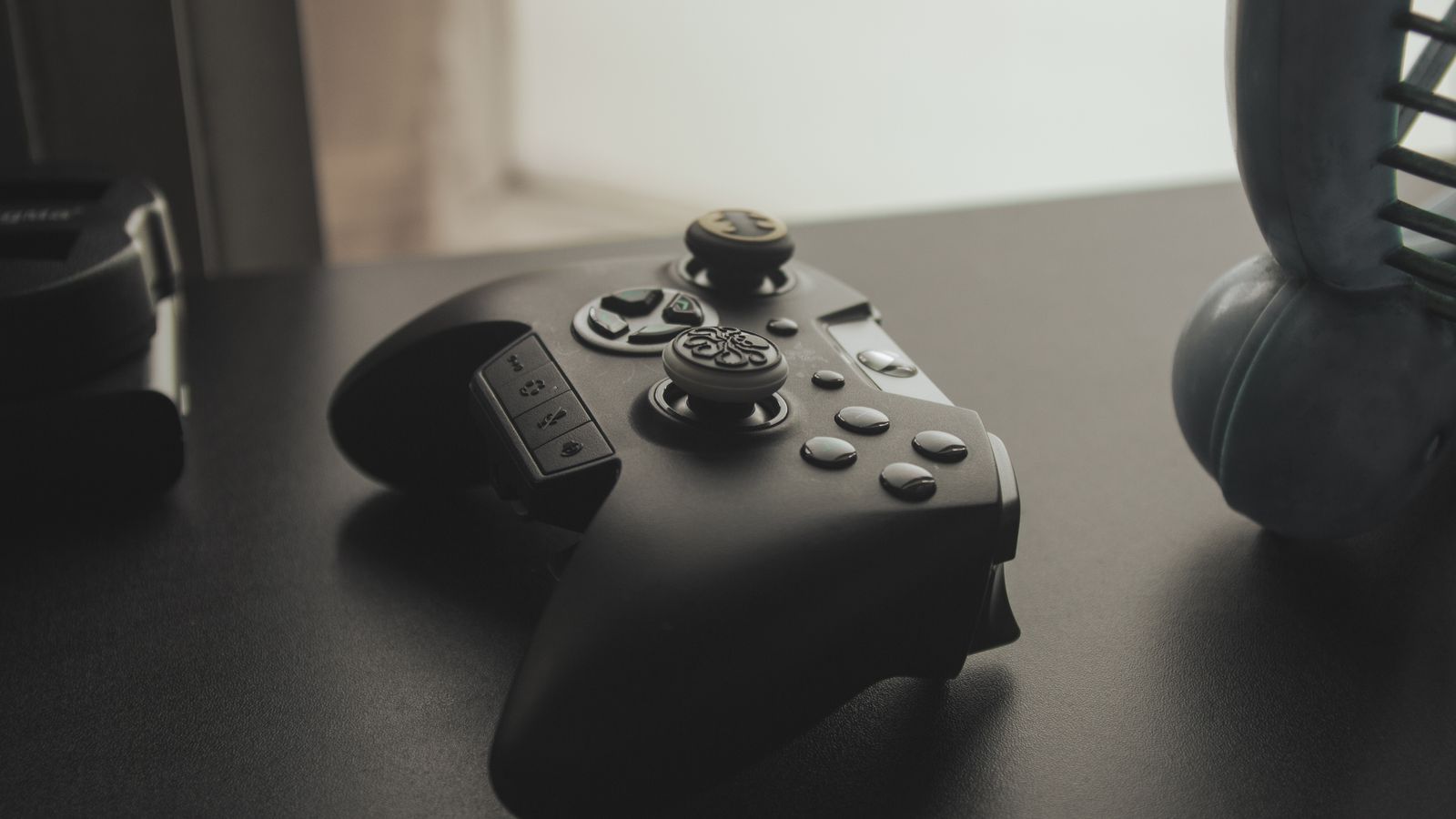 A black game controller resting on a dark table