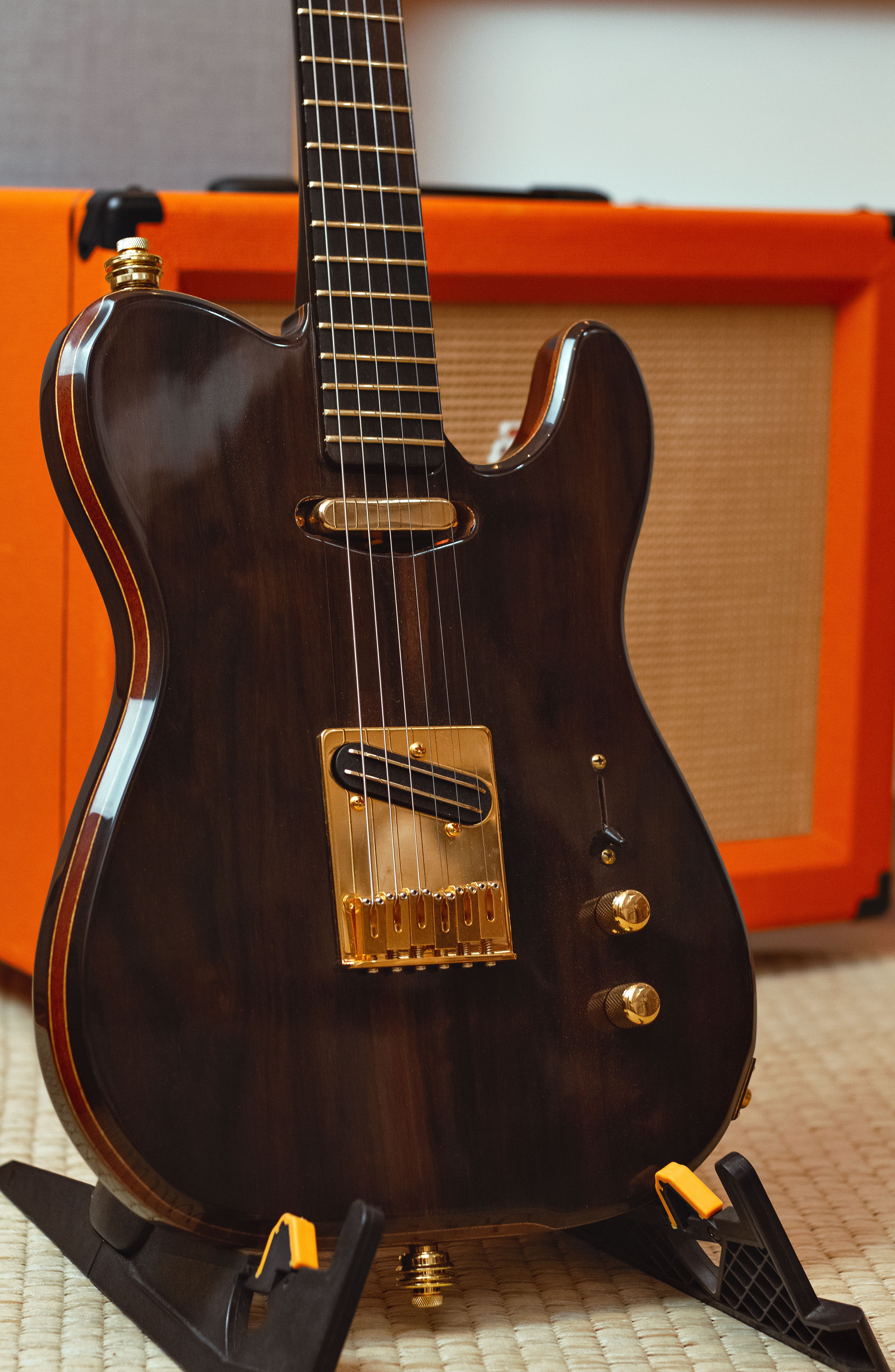 Close-up of an elegant dark electric guitar with gold accents and amplifier.
