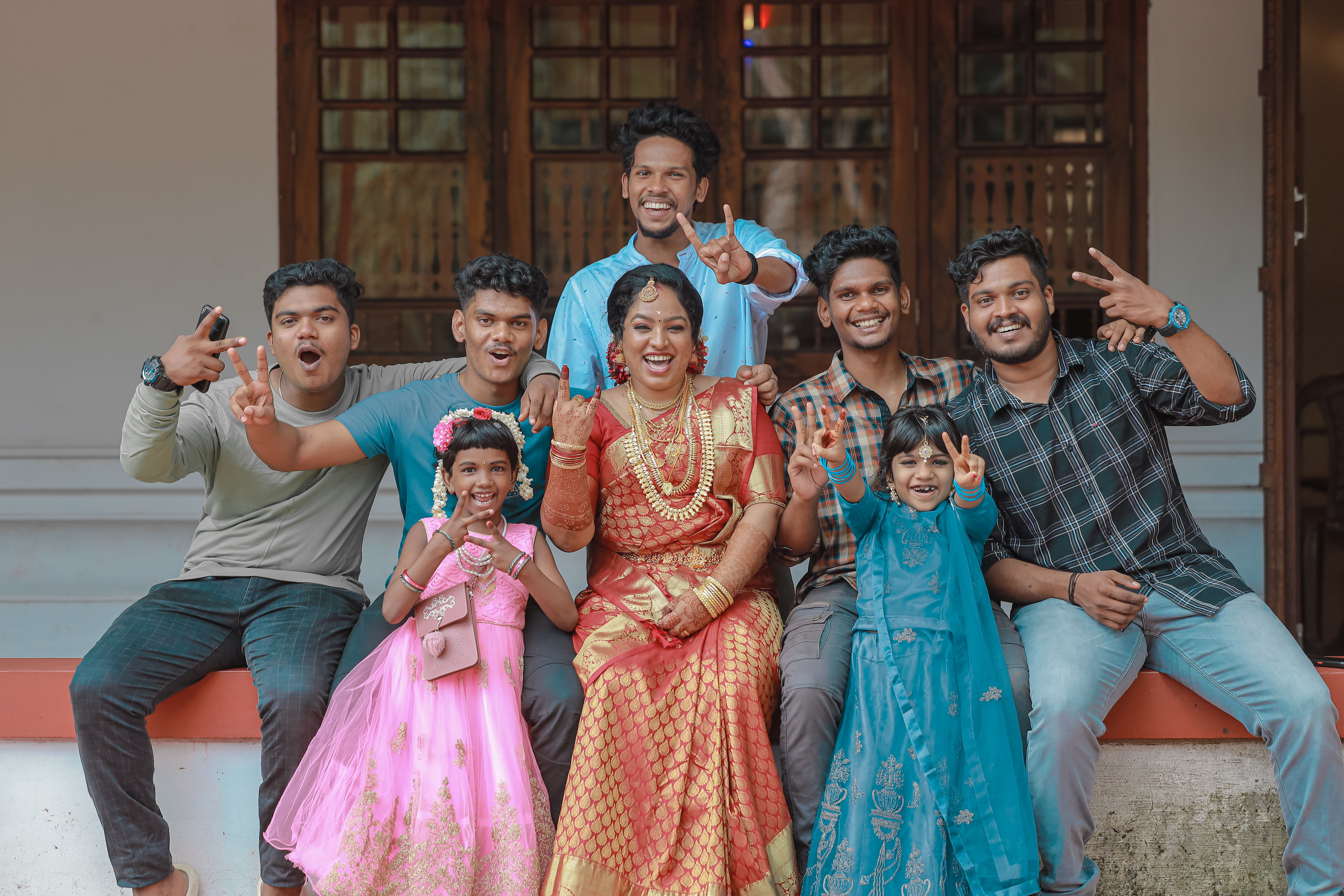 Smiling group of people in traditional Indian clothing posing outdoors with vibrant expressions.
