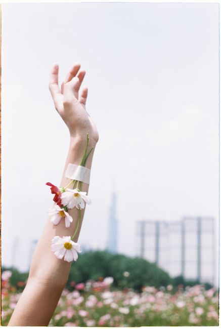 A raised arm decorated with flowers in a blooming summer landscape.