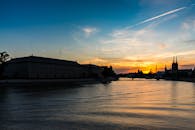 城市剪影映在宁静的河面上，倒映着绚烂的日落