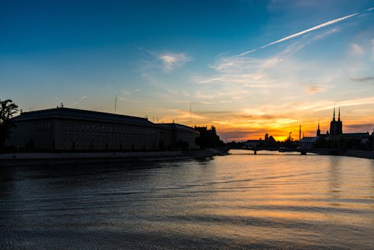 城市剪影映在宁静的河面上，倒映着绚烂的日落