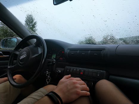 雨天，车内视角可见方向盘和仪表盘，挡风玻璃上落着雨滴