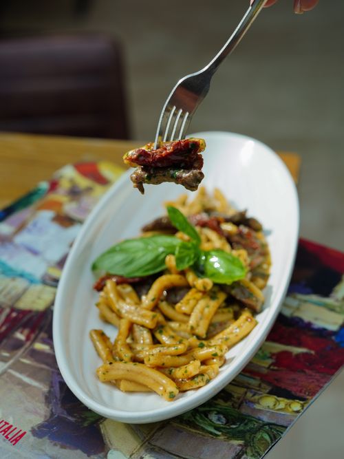 Free Close-up of basil pesto pasta with sun-dried tomatoes on a white plate. Stock Photo