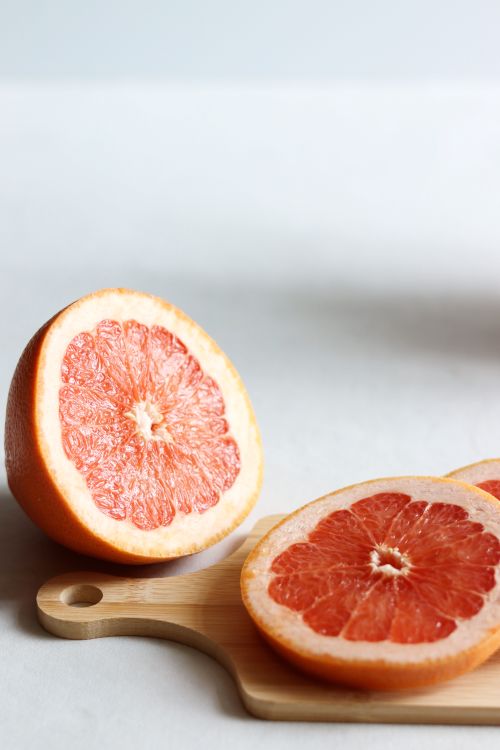 Free Juicy grapefruit slices displayed on a wooden cutting board, showcasing fresh and healthy citrus fruit. Stock Photo