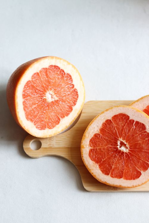 Free Vibrant slices of juicy grapefruit on a wooden cutting board, perfect for healthy eating. Stock Photo