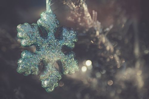 Free Close-up of a glittery snowflake ornament hanging on a Christmas tree branch. Stock Photo