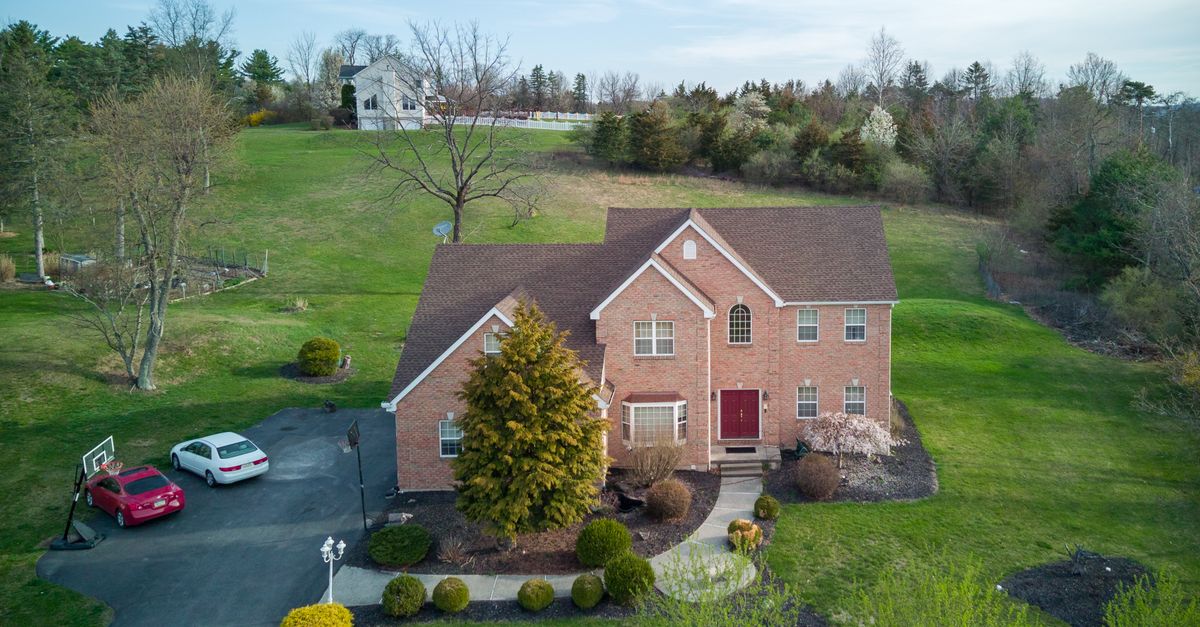 Aerial view of a brick house surrounded by trees and lawn in Tannersville, PA.