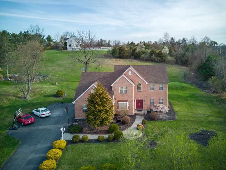 Aerial view of a brick house surrounded by trees and lawn in Tannersville, PA.