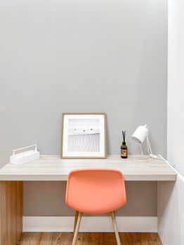 Elegant minimalist home office setup featuring a wooden desk, orange chair, and modern decor.