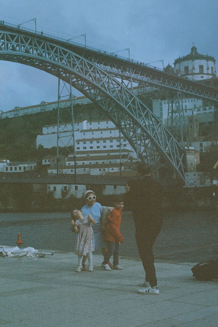 Man Taking Photo Of Kids Posing Against Luis I Bridge In Porto, Portugal