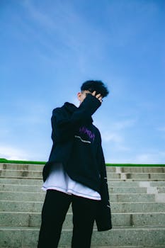 Fashionable young man poses on outdoor stairs on a sunny day.