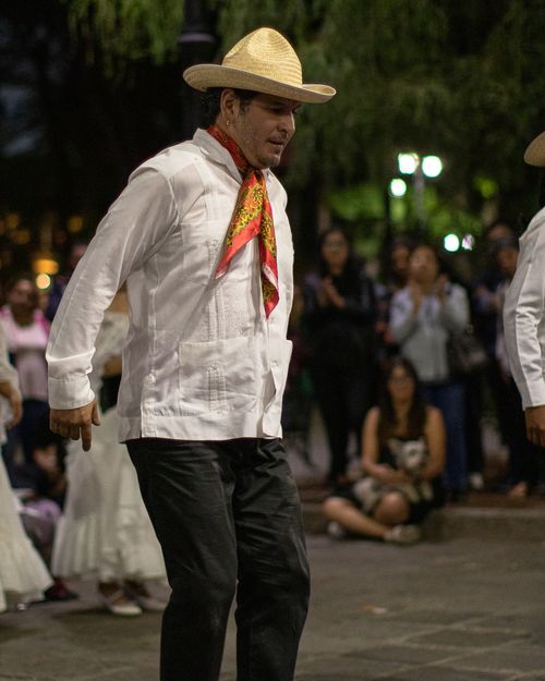Free A man in traditional clothing dances during a vibrant Mexican street festival at night. Stock Photo
