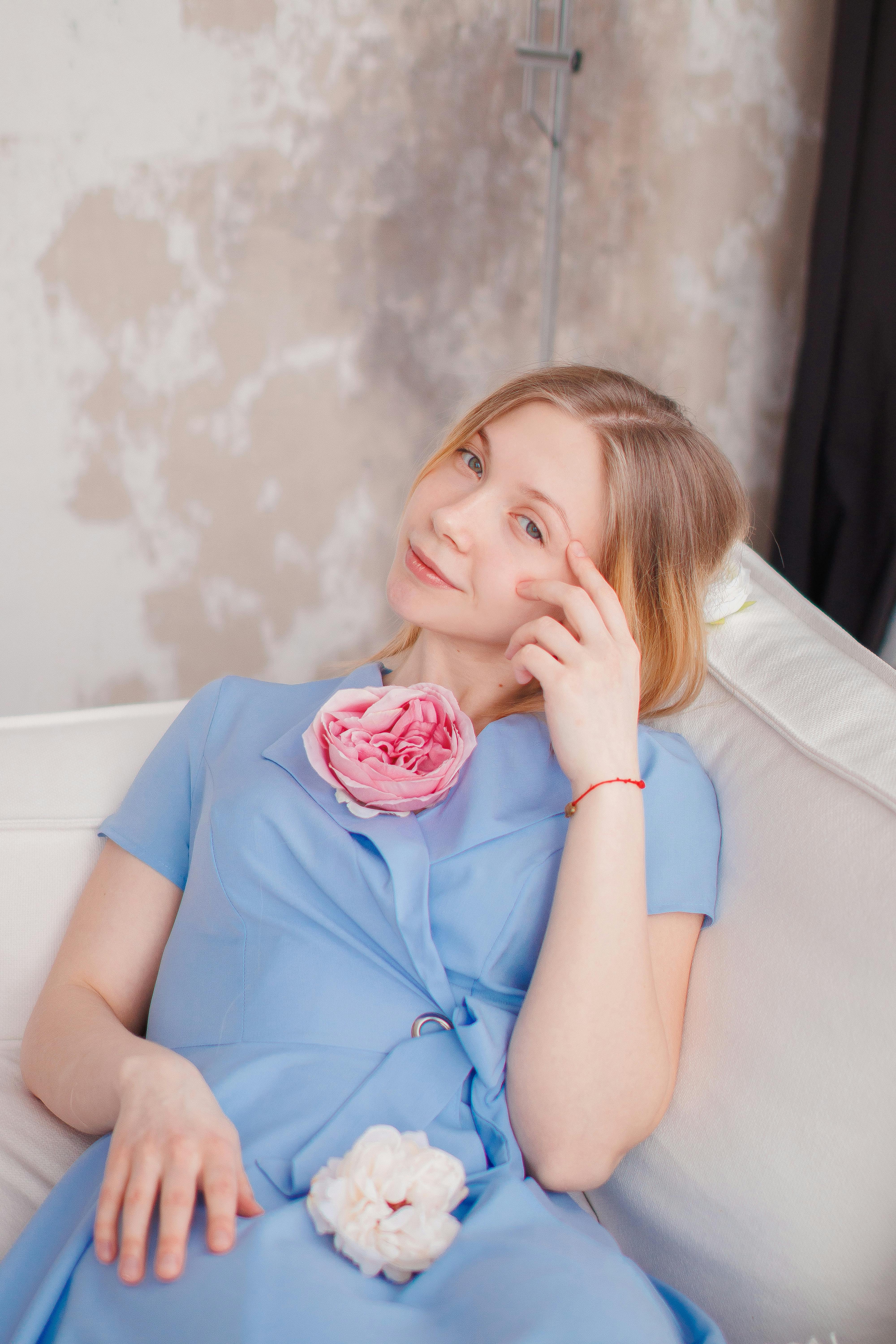 young woman in a blue dress sitting on a sofa