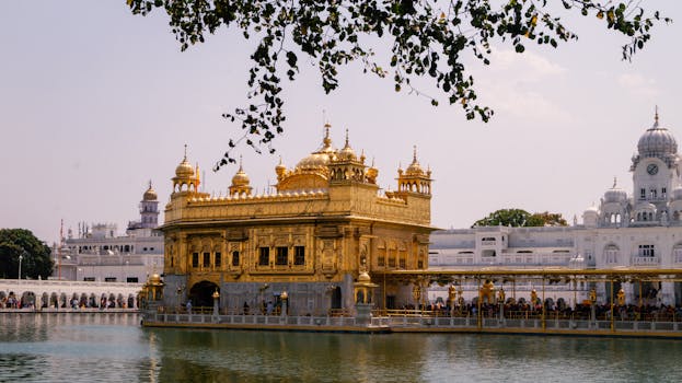Golden Temple in Amritsar, Punjab, reflected in water under clear skies, showcasing stunning architecture.