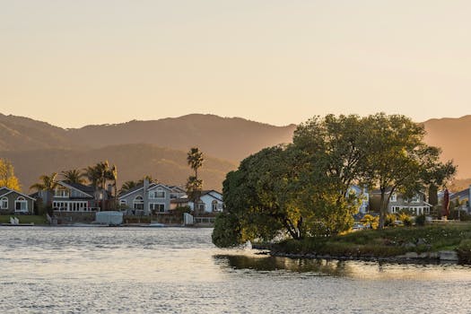 Picturesque lakeside town with a tree at sunset, capturing a tranquil atmosphere.