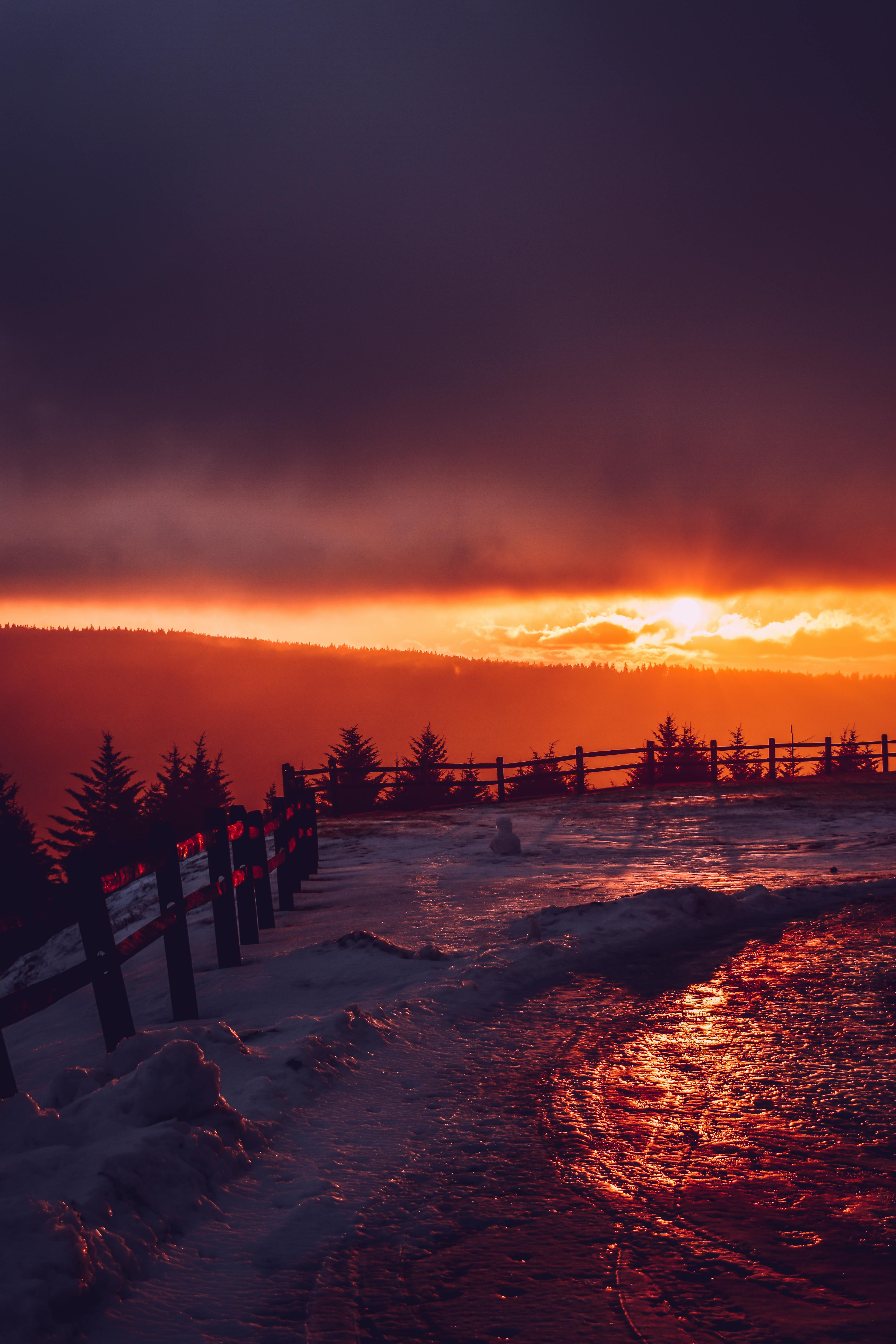 在雪地地形和轮廓围栏背后，日落令人惊叹，捕捉到冬天的宁静之美