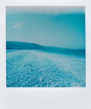 A tranquil beach scene with a vintage polaroid effect, capturing the sea, shore, and sky.