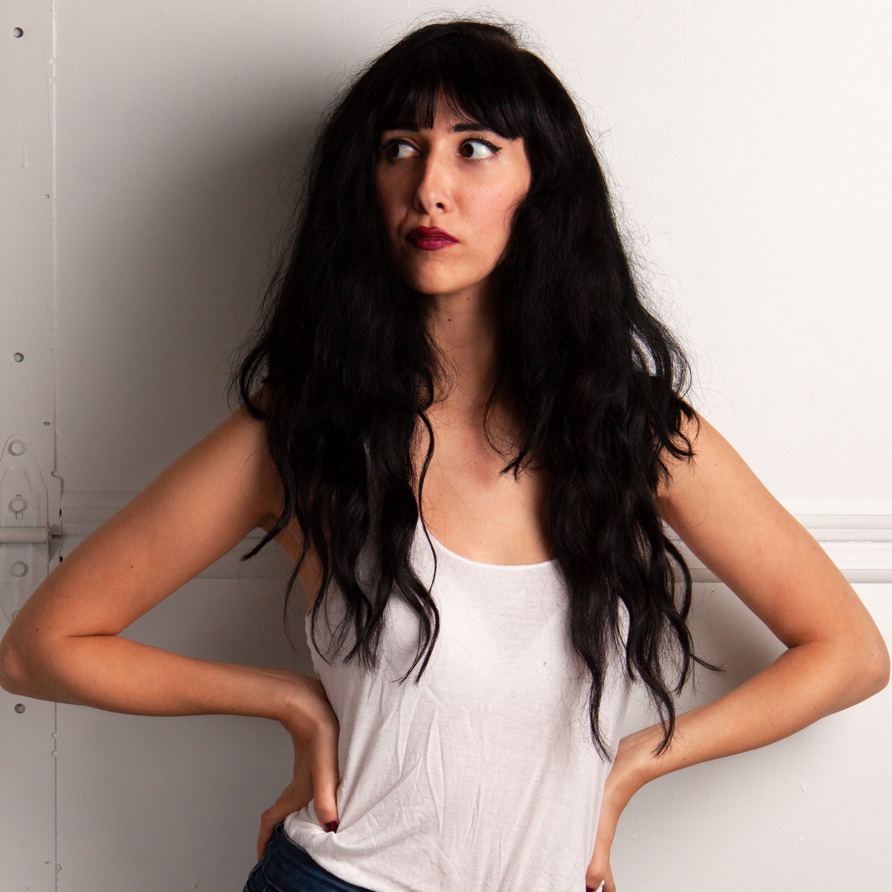 Stylish brunette woman posing confidently in casual attire against a white backdrop.