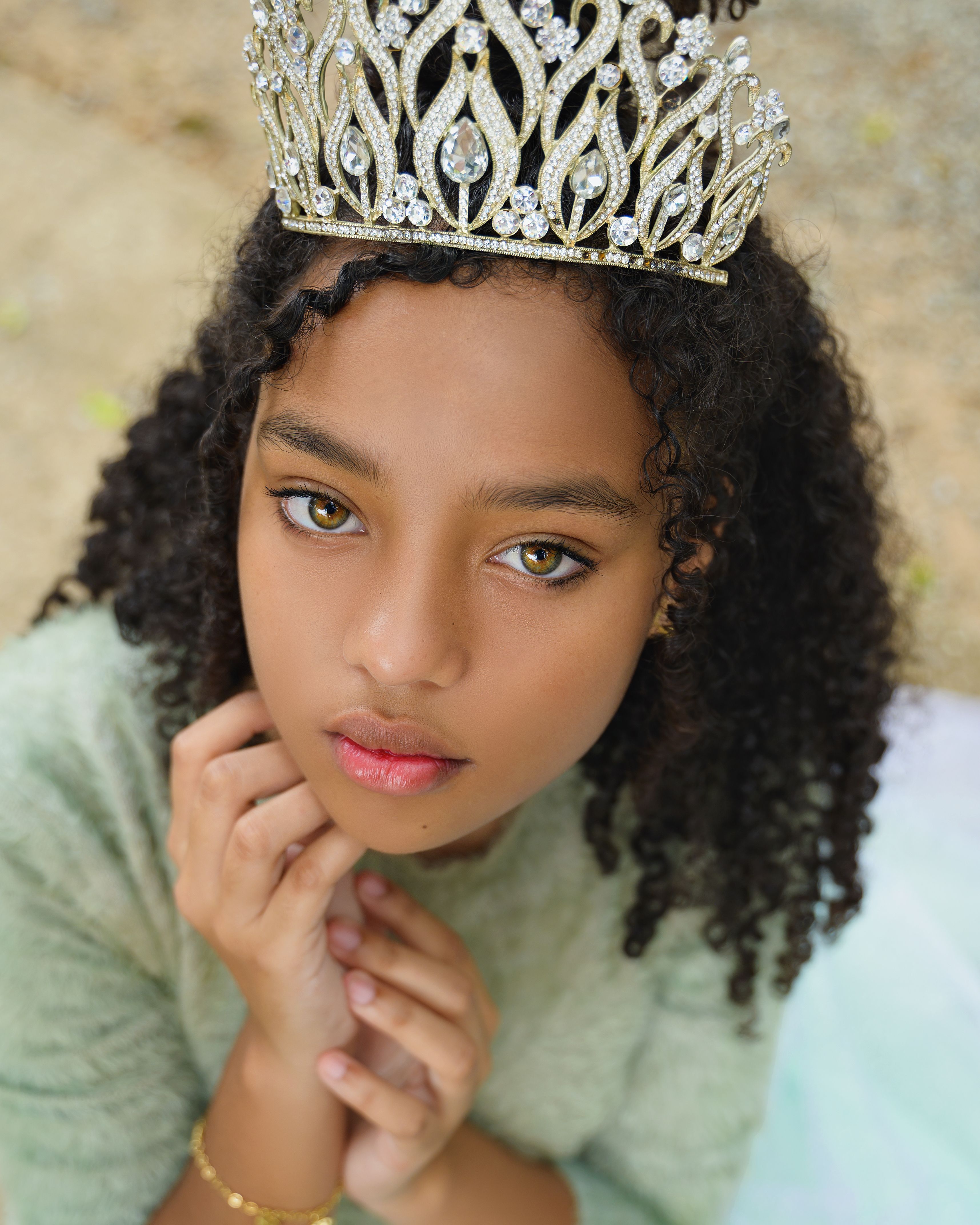 Elegant portrait of a young girl wearing a delicate tiara, showcasing her natural beauty and curly hair.