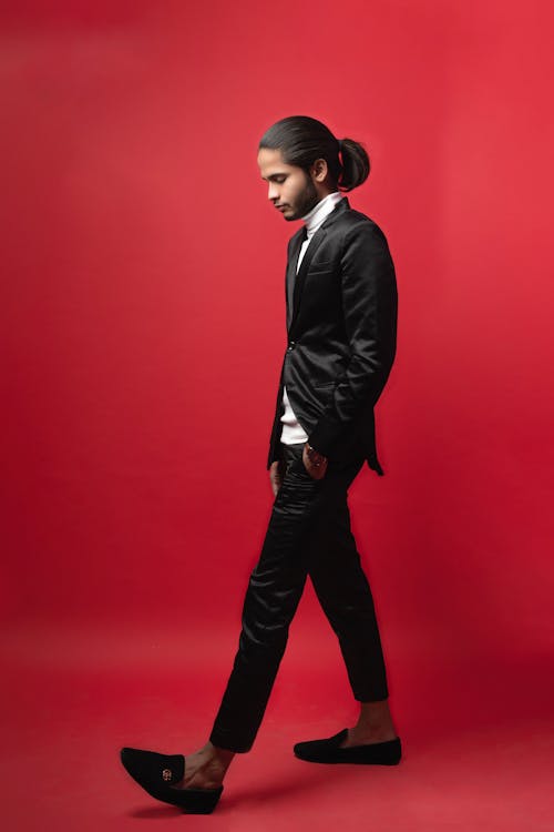Young Man in a Black Outfit Posing in Studio on Red Background 