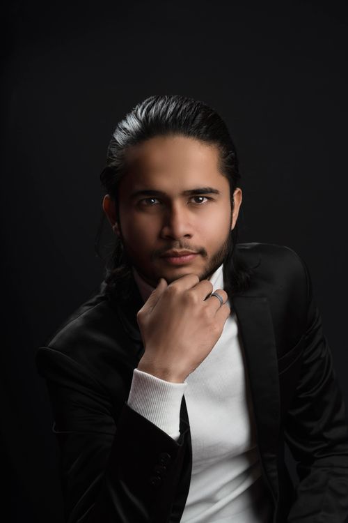 Free Studio portrait of a young man with dark hair in a black suit, showcasing modern fashion and style. Stock Photo