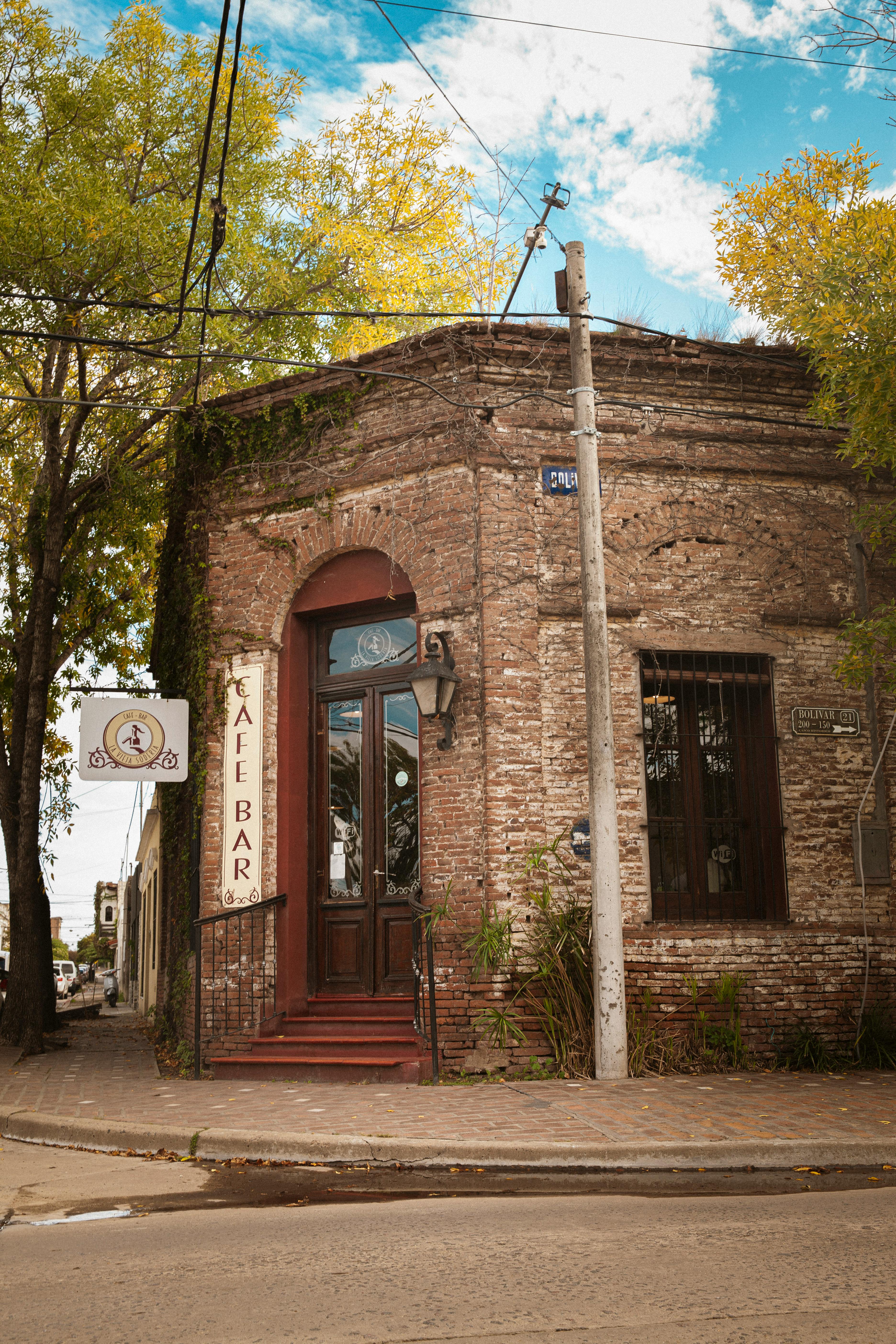 Rustic brick cafe entrance surrounded by fall foliage in a charming city street setting.