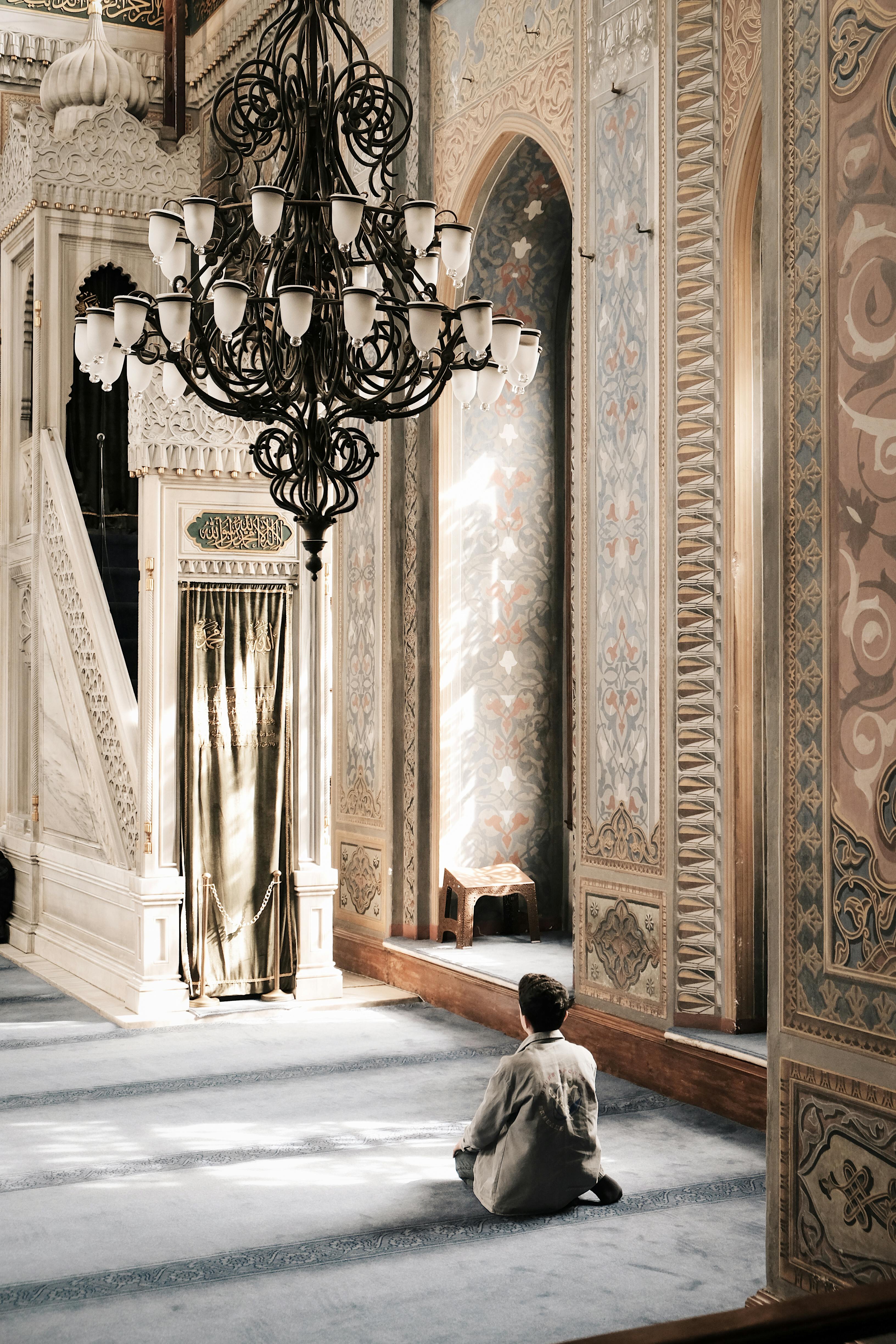 guy sitting on floor praying in mosque