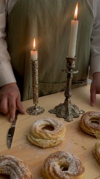 A baker arranging pastries on a table with elegant candleholders and candles, creating a cozy atmosphere.