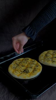 Close-up of a hand sprinkling seeds on dough, ready for baking. Food preparation process.