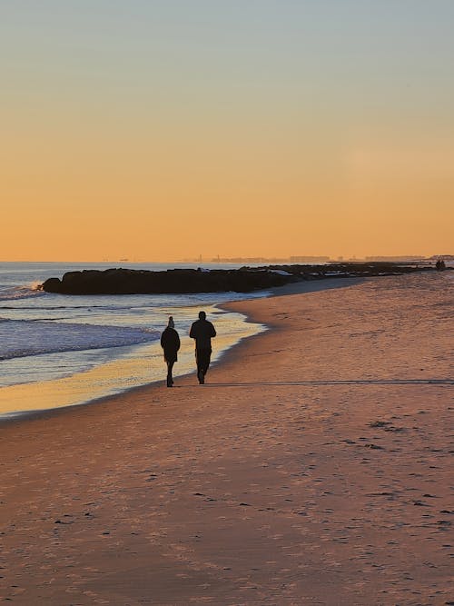 People Walking on Beach at Sunset