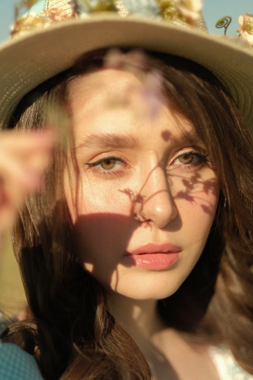Free Close-up portrait of a woman wearing a hat with flower shadows on her face, in sunlight. Stock Photo