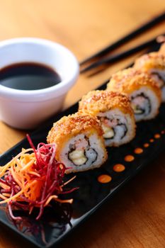 Close-up of crispy sushi rolls with sauce and colorful garnish, perfect for food lovers.