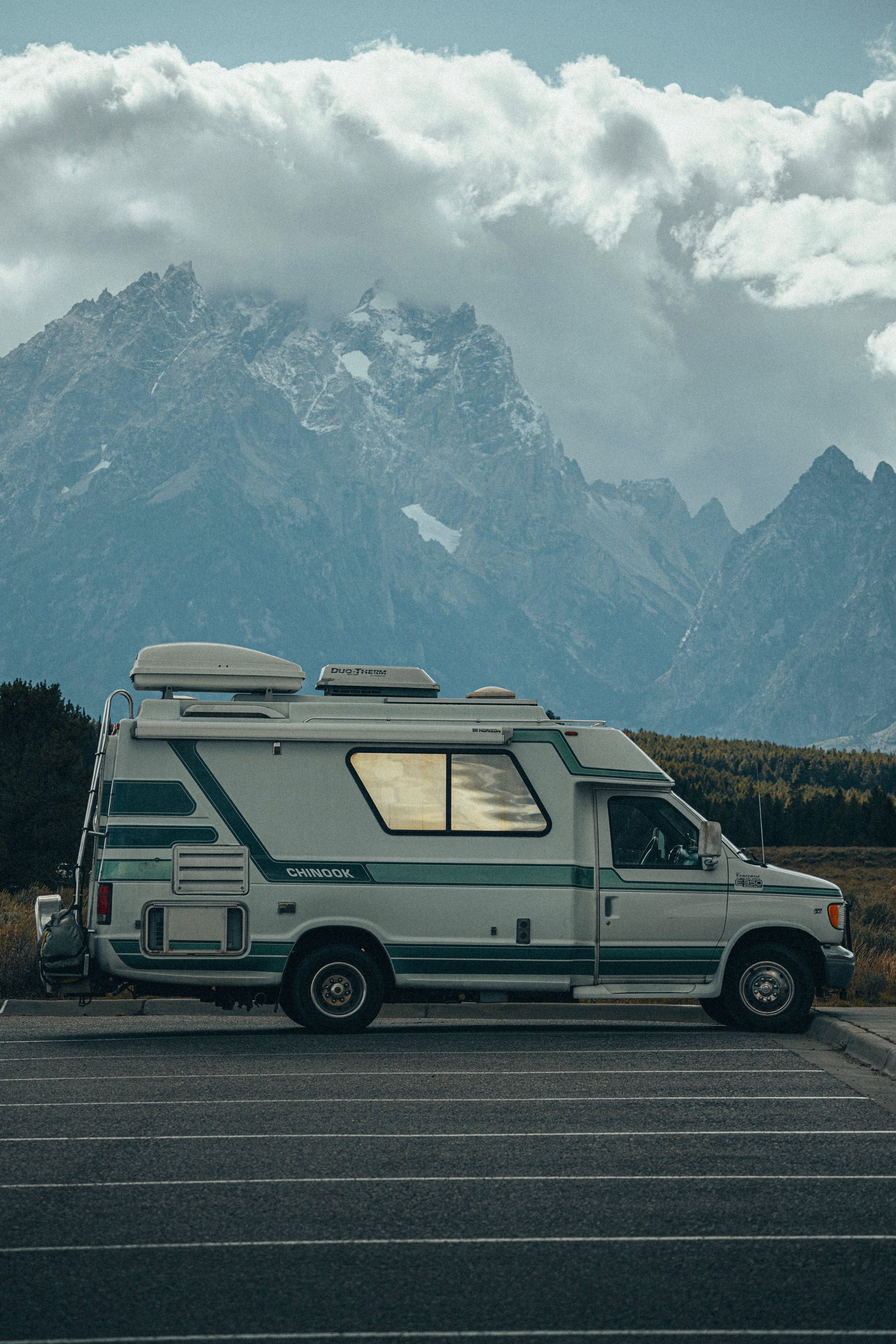 Explore the great outdoors in a camper van parked in front of a striking mountain range.