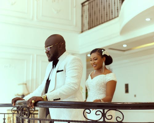 Elegant Groom and Bride Standing by Railing in Hotel