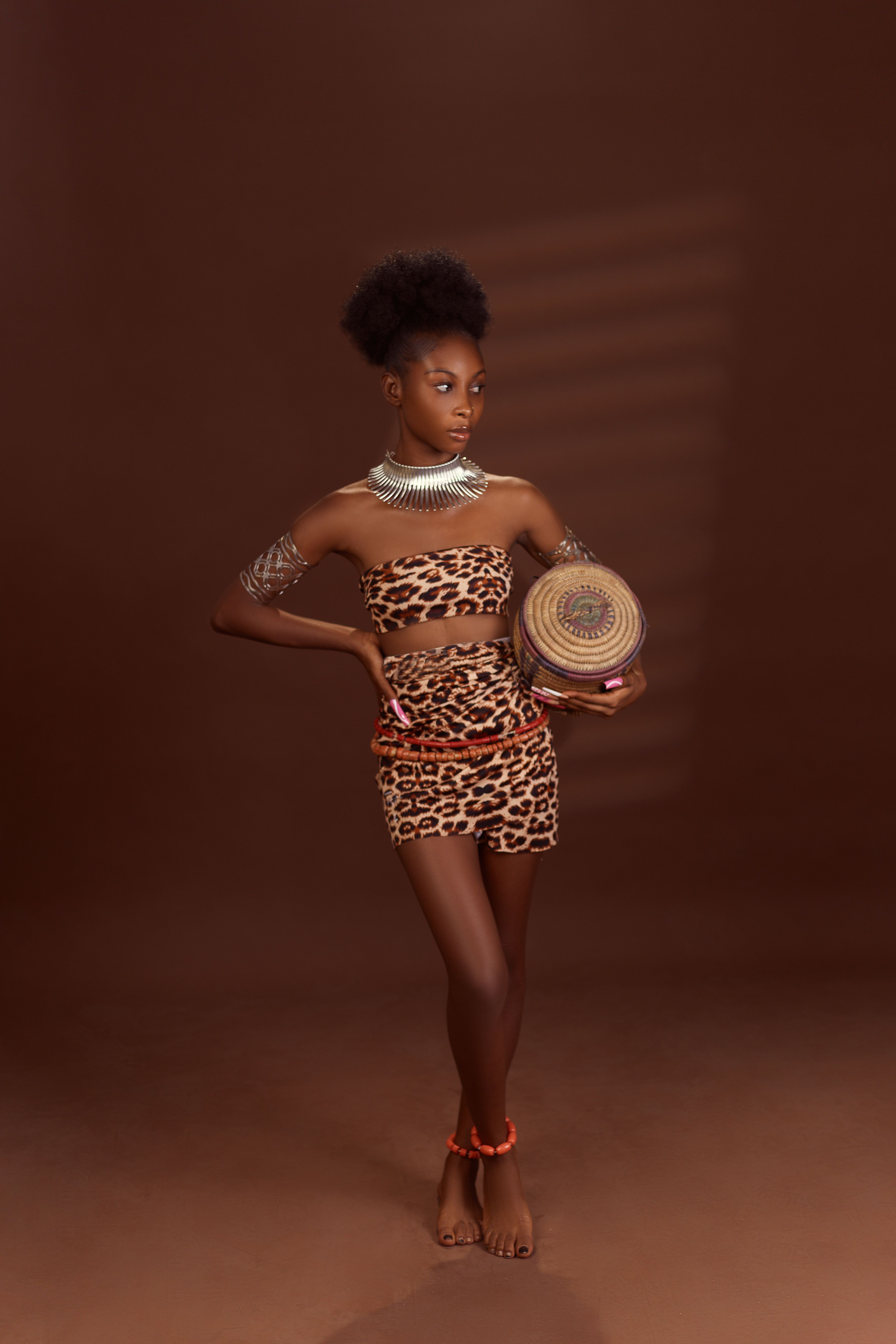 Elegant woman in animal print attire posing with tribal accessories in a studio setting.