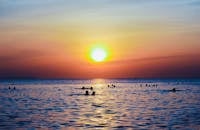 人们在色彩缤纷的日落天空下游泳