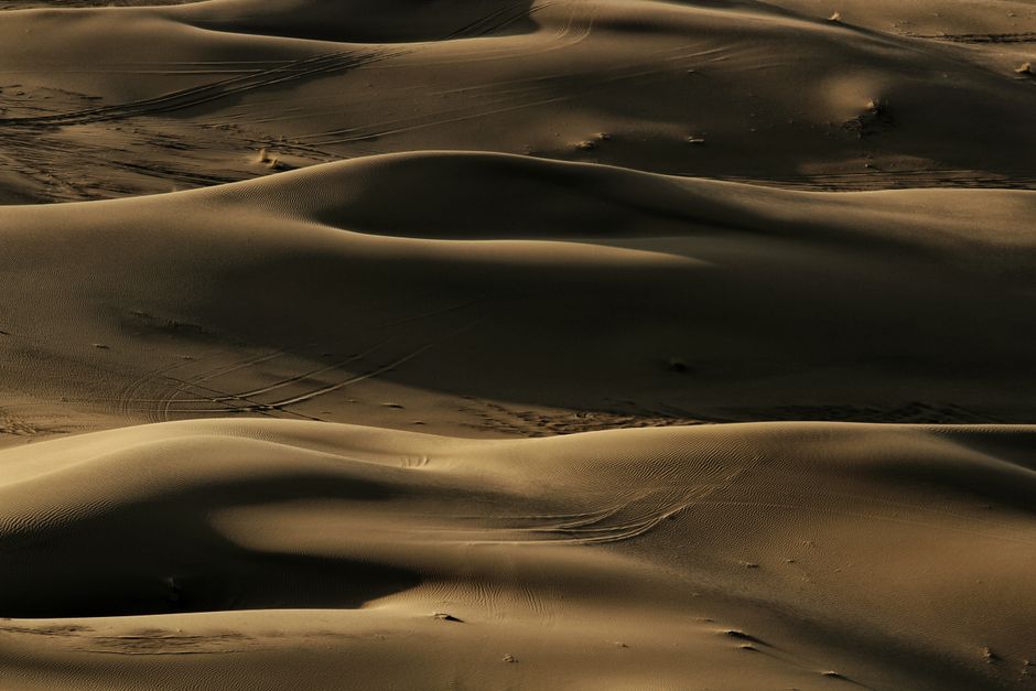 Aerial view of golden sand dunes in Kashan, capturing the serene desert landscape under warm light.