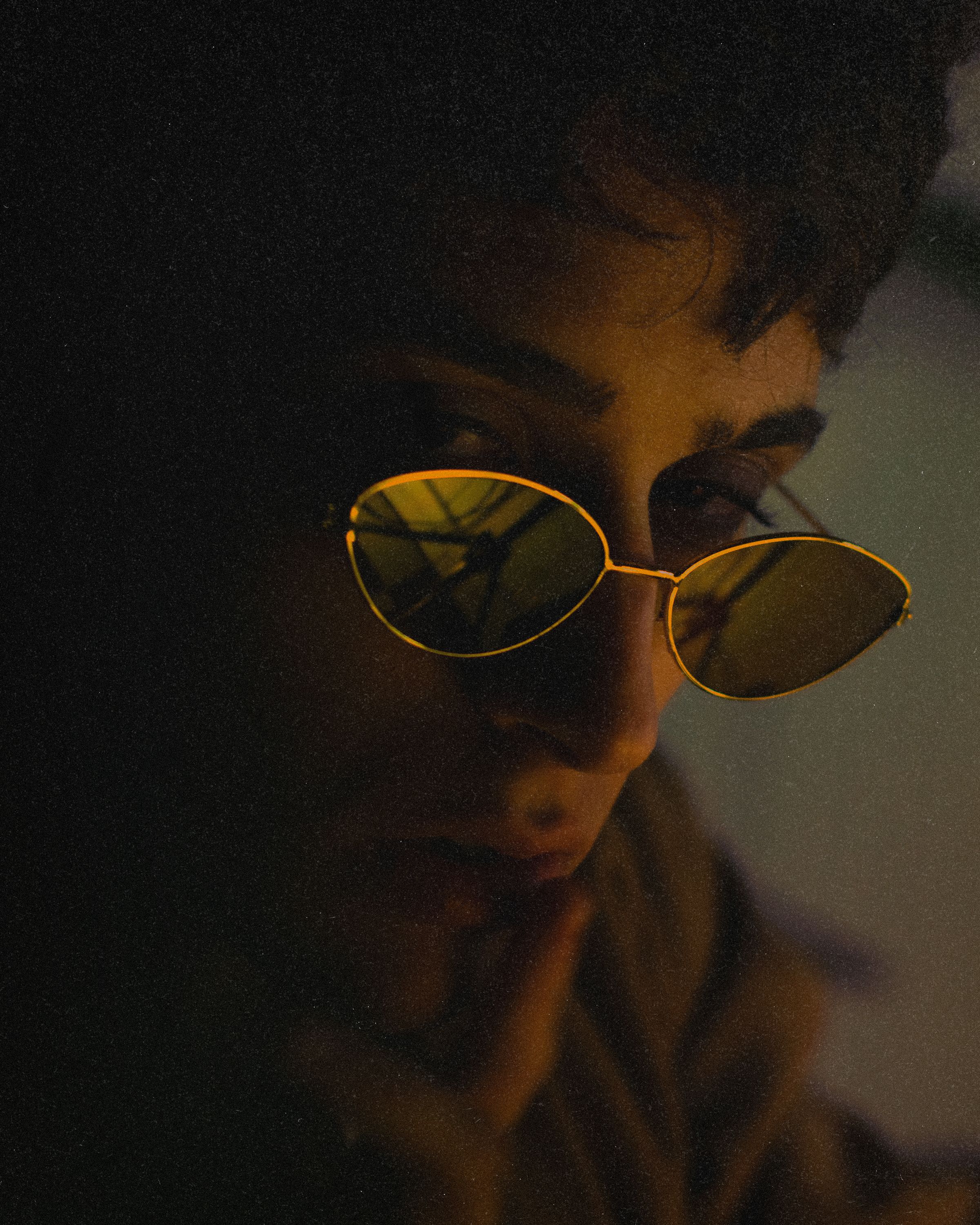 A mysterious close-up portrait of a person in sunglasses, set in a dark ambiance.