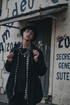 Stylish young man posing against graffiti-covered urban wall.