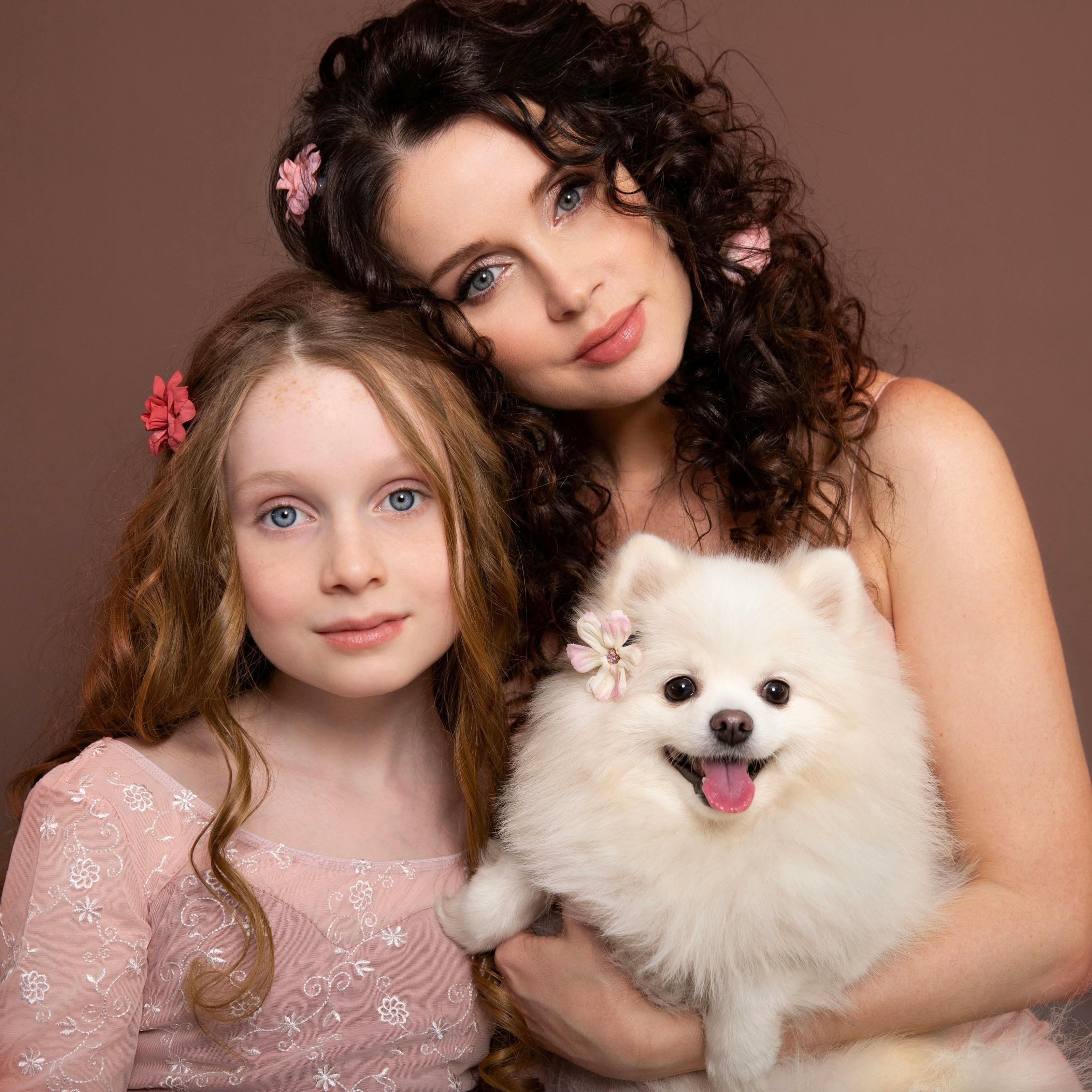 elegant mother posing with daughter and white dog