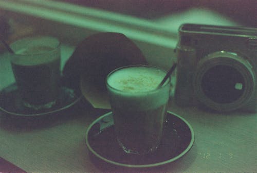 Free Coffee in Glasses and Camera on Table Stock Photo