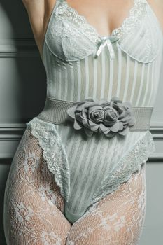 A close-up of a woman wearing a stylish lace bodysuit with floral belt detailing.