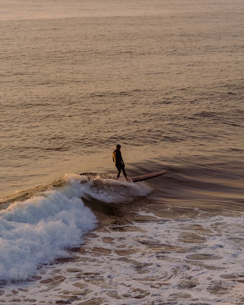 Man Surfing on Ocean Wave on Sunset