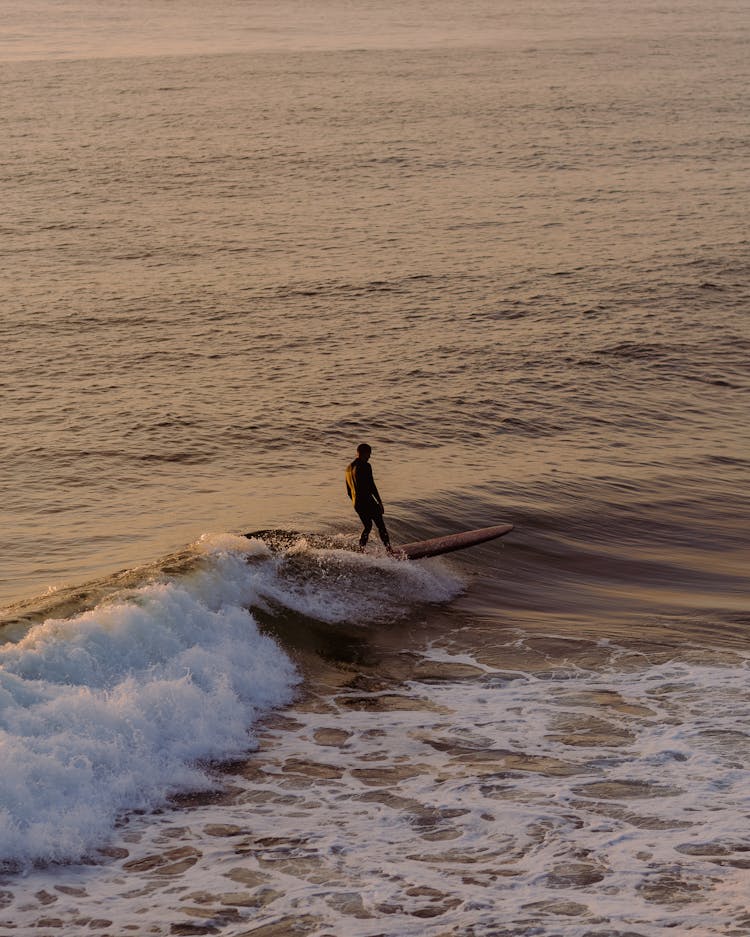 Man Surfing On Ocean Wave On Sunset